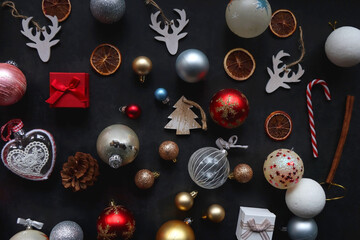 Various colorful Christmas ornaments on dark background, top view.