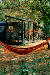 Hammock tied to trees on the territory of campsites with motorhomes for rest and relaxation of travelers