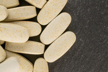 Several medical pills  on slate stone, macro, top view.