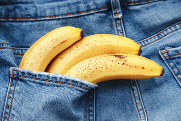 Bananas in blue trousers pocket. Lunch snack background. Jeans rear pocket. Ripe yellow banana with...