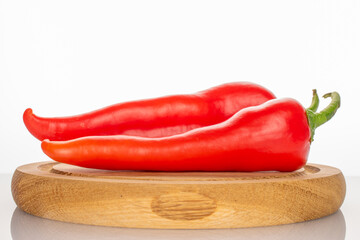 Two sweet red peppers on a wooden tray, macro, isolated on white background.