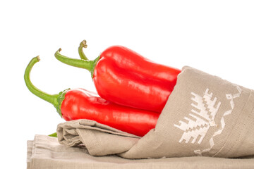 Three red sweet, organic peppers with a linen napkin, close-up, isolated on white.
