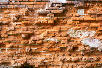 An old brick wall with bricks that are badly crumbling from time