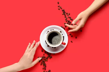 Stickers pour porte Bar a café Female hands with cup of hot coffee and beans on red background