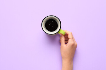 Woman holding cup of hot coffee on lilac background