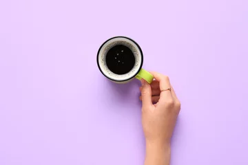  Woman holding cup of hot coffee on lilac background © Pixel-Shot