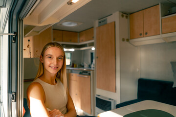 A beautiful girl rides in a trailer on a trip looks out the open window and smiles sincerely from beautiful views along the way