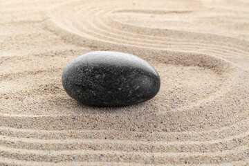 Fototapeta na wymiar Black stone on sand background. Zen concept.