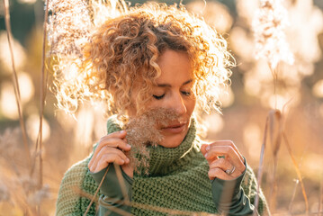 Portrait of attractive woman enjoying emotions in outdoor leisure activity alone in a golden field during sunny day and sunset light. People and interior life balance mental wellbeing. Eyes closed