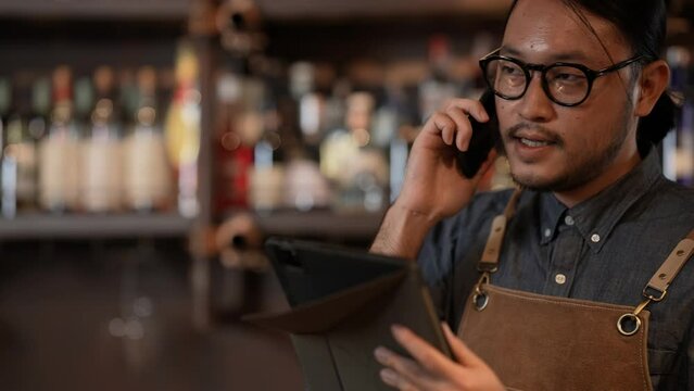 Night club concept of 4k Resolution. The bartender is taking orders from customers with the phone in the restaurant. A group of specialized clubs that sell alcoholic beverages.