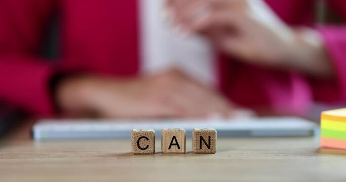 Can't and can on wooden cubes in the office, shallow focus. Women's hands take the letter, motivation