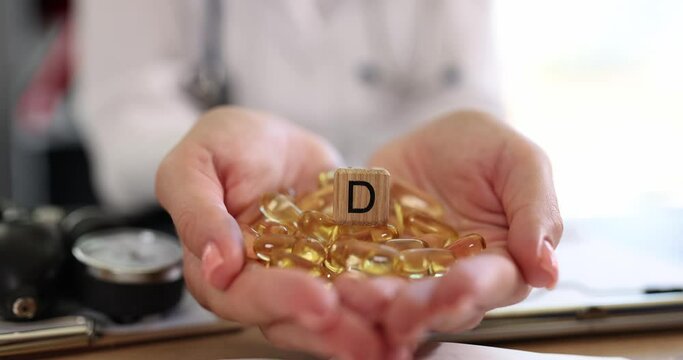 Yellow capsules of vitamin D3 in the hands of a doctor, close-up. Healthy nutrition, body support, slowmotion