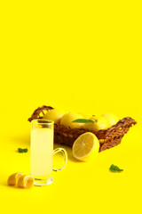 Shot of tasty Limoncello and wicker basket with citrus fruits on yellow background