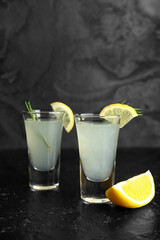 Shots of tasty Limoncello with rosemary on black background