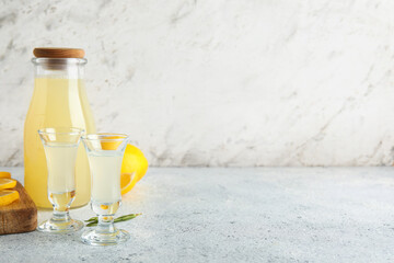 Bottle and shots of tasty Limoncello on white background