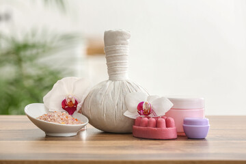Composition with cosmetic products, herbal massage bag and orchid flowers on wooden table