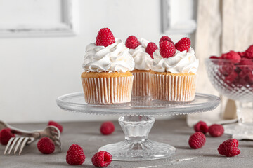 Stand with tasty raspberry cupcakes on table