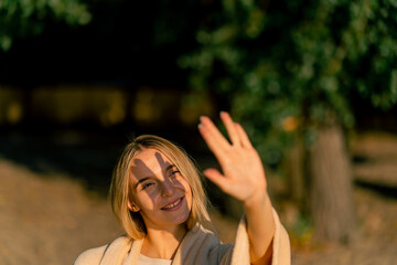Naklejka premium A beautiful peaceful girl covers herself with a blanket on the river bank near park and squints from the setting sun