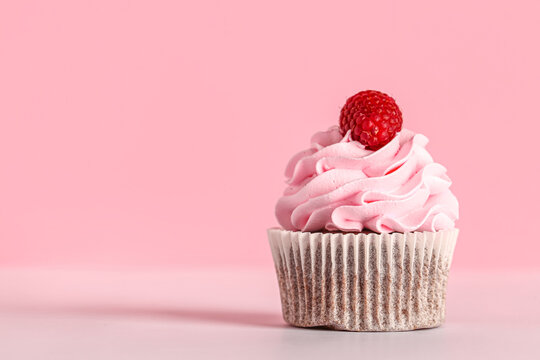 Tasty raspberry cupcake on pink background