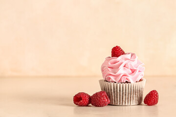 Tasty raspberry cupcake and fresh berries on beige background