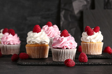 Boards of tasty raspberry cupcakes on black background