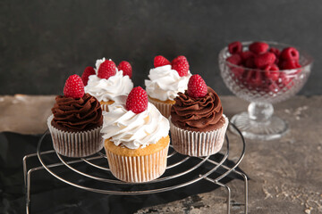 Grid of tasty cupcakes with raspberries on table