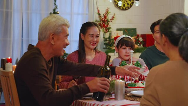 Asian christian family on christmas night at home. Enjoying Thanksgiving meal. Dinner party celebration with turkey enjoying holiday. Happy New Year. Share food and wine, Laughing and having fun.