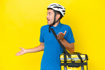 Young handsome man with thermal backpack over isolated yellow background with surprise facial expression