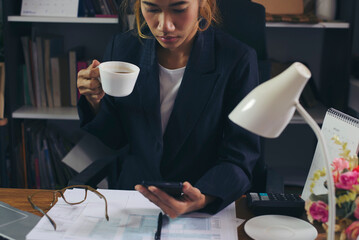 Businesswoman working online via smartphone and drink coffee at business home office. Woman...