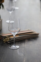 An empty glass of wine on the wooden table with the menu at the back