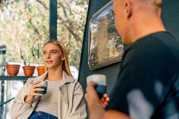 A young beautiful girl drinks tea and talks with her boyfriend while sitting on the terrace near a...