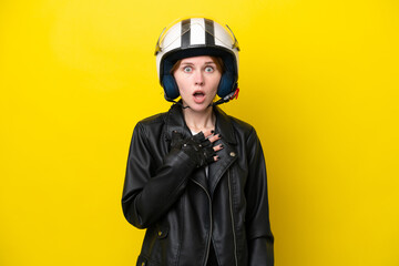 Young English woman with a motorcycle helmet isolated on yellow background surprised and shocked while looking right