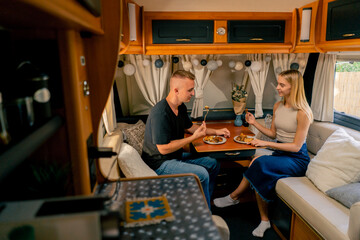 Fototapeta na wymiar Couple in love together on a date in a mobile home sitting at the table and having dinner in romantic setting