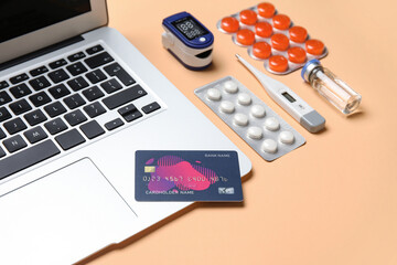 Laptop, credit card and items from first aid kit on beige background