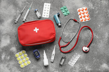 First aid kit and pills on grunge grey background
