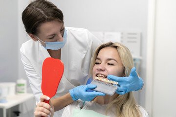 dentist with tooth color samples palette choosing shade for patient teeth in a dental clinic, dentistry healthcare concept