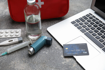 Laptop, credit card and first aid kit on grunge grey background