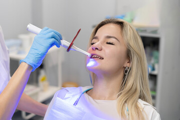 young girl on a teeth whitening treatment, using ultraviolet lamp for bleaching