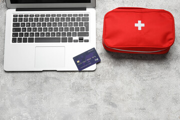 Laptop, credit card and first aid kit on grunge grey background