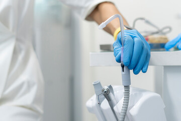 female dental doctor taking a tool equipment from instrument panel on a dentist's chair