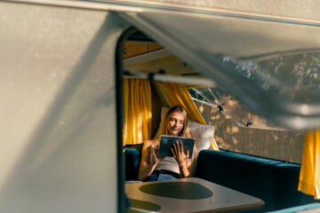While traveling on a trailer a young girl lies on the sofa by the window in the car and reads book...