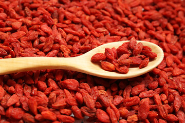 Composition with spoon and red dried goji berries as background