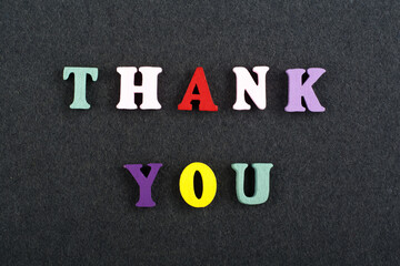 THANK YOU word on black board background composed from colorful abc alphabet block wooden letters, copy space for ad text. Learning english concept.