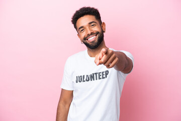 Young volunteer man isolated on pink background pointing front with happy expression