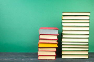 Books on wooden table, on a green background. Back to school. Copy space for text. Education background.