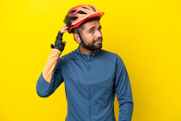 Young cyclist Brazilian man isolated on yellow background having doubts