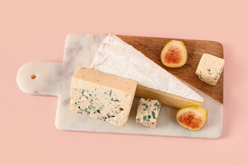 Board with tasty cheese and fig on pink background
