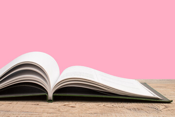 open book. Composition with hardback books, fanned pages on wooden deck table and pink background. Books stacking. Back to school. Copy Space. Education background.