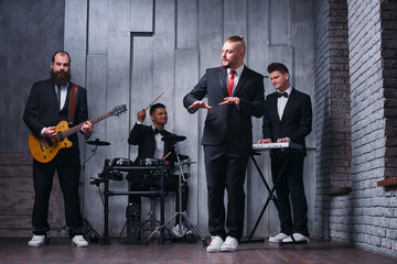 Music band and fashion.  Handsome young men in suits playing rock and singing song.