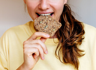 Woman eating grain bread close-up. Healthy eating and diet background.